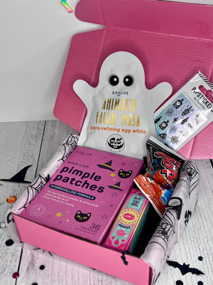 Pink box with skincare products including a ghost-shaped mask and pimple patches on a white background.