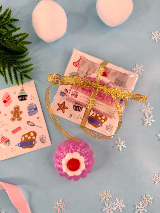 Pink gift with gold ribbon on a blue surface with snowflakes