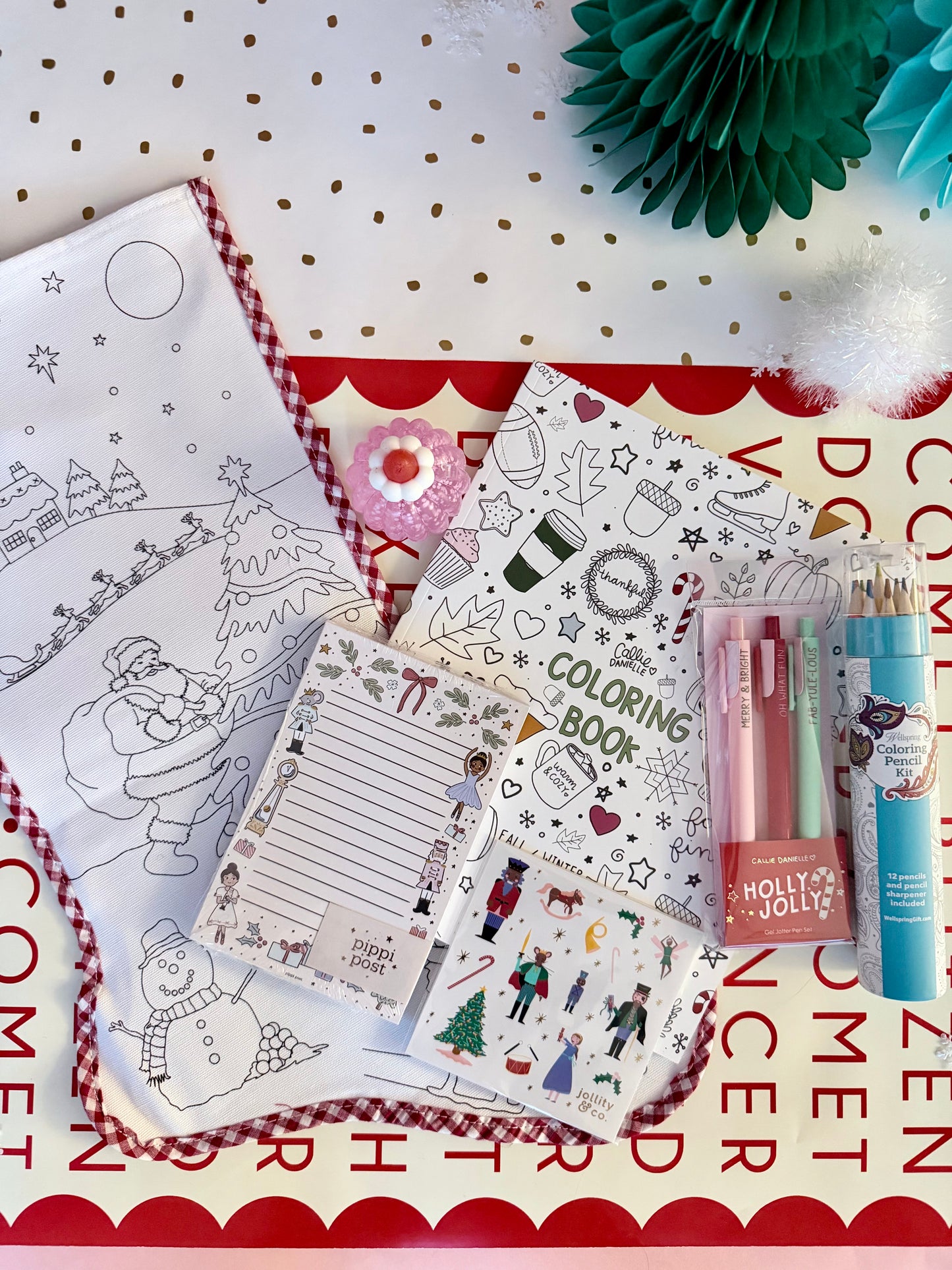 Coloring book with Christmas-themed pages and stationery items on a white surface.