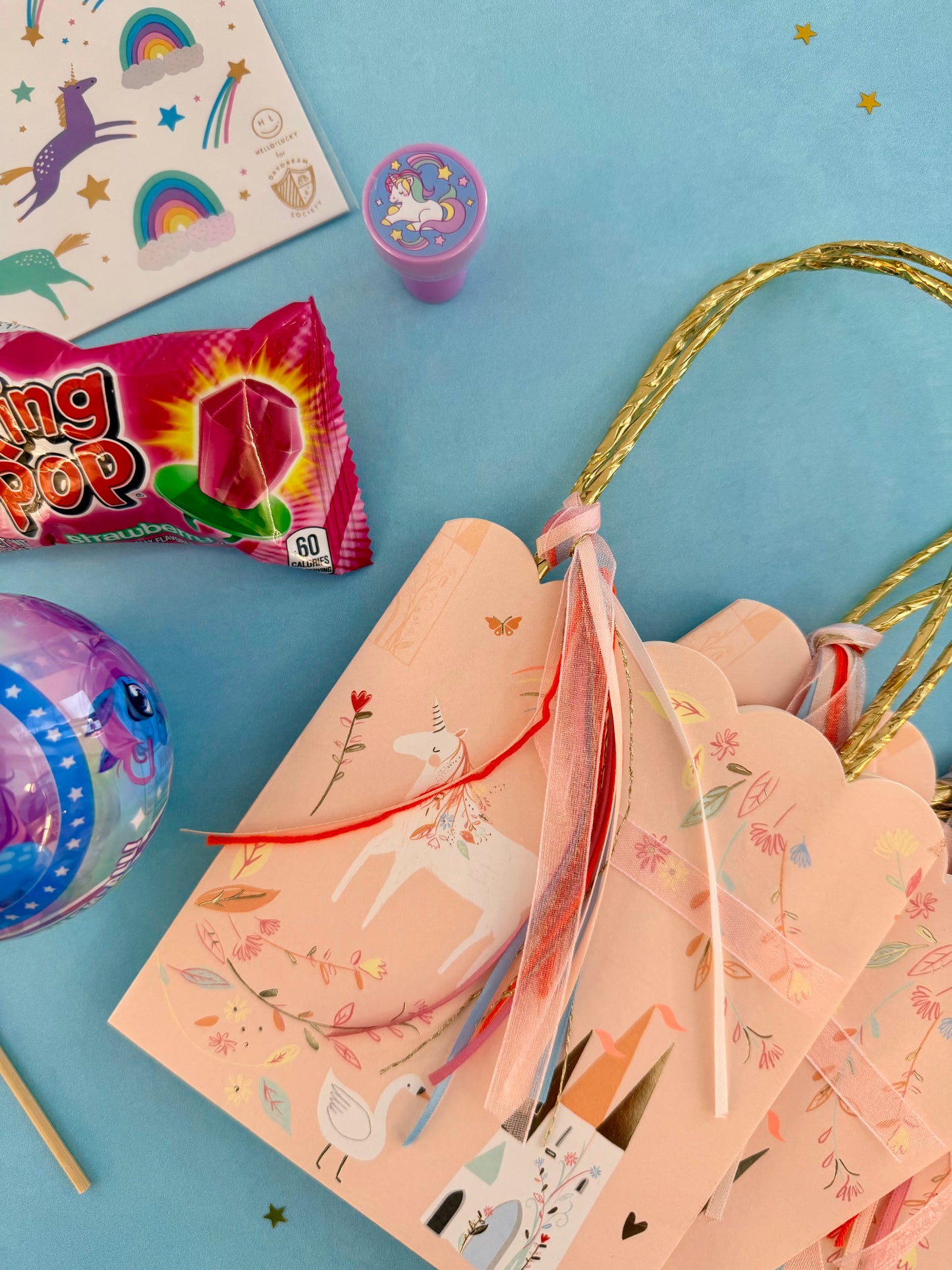 Unicorn-themed party supplies including plates, cups, and a bag on a blue background.