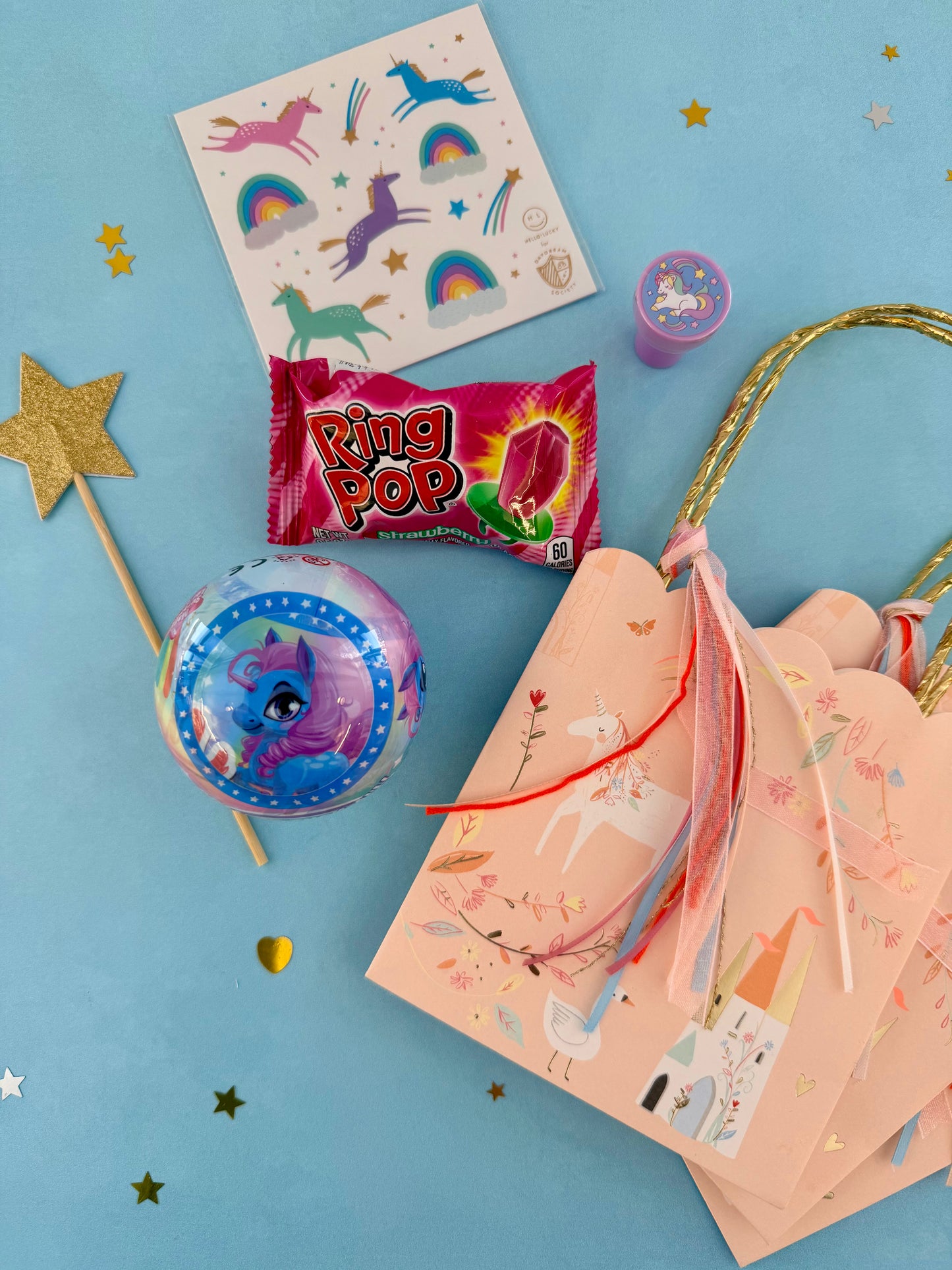 Colorful party supplies including a Ring Pop candy, balloons, and decorative items on a blue background.