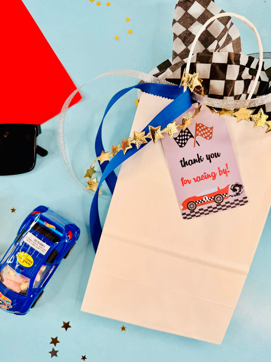 Gift bag with race car-themed tag and toy car on a blue background