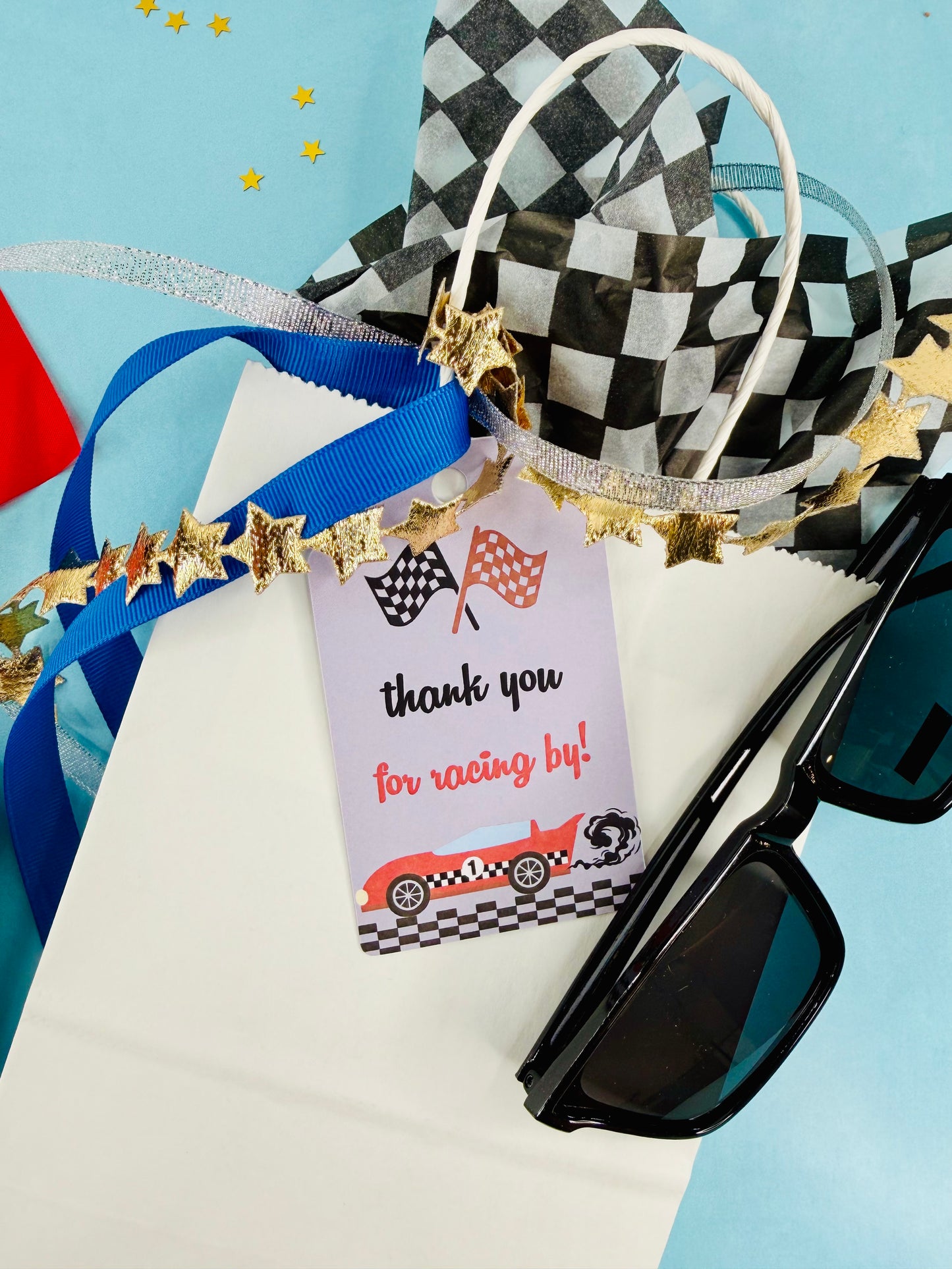 Gift bag with sunglasses, ribbons, and a 'thank you' tag on a blue background