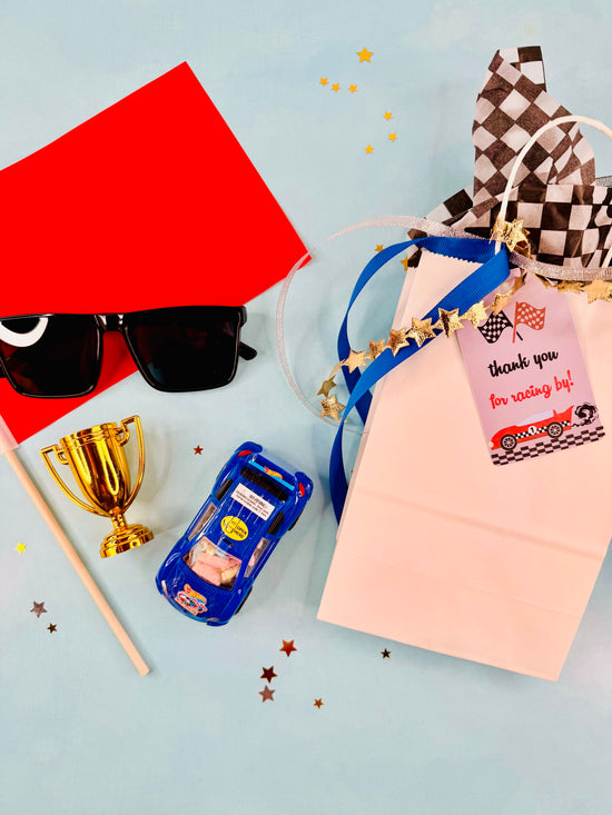 Gift bag with toy car, trophy, and sunglasses on a blue background