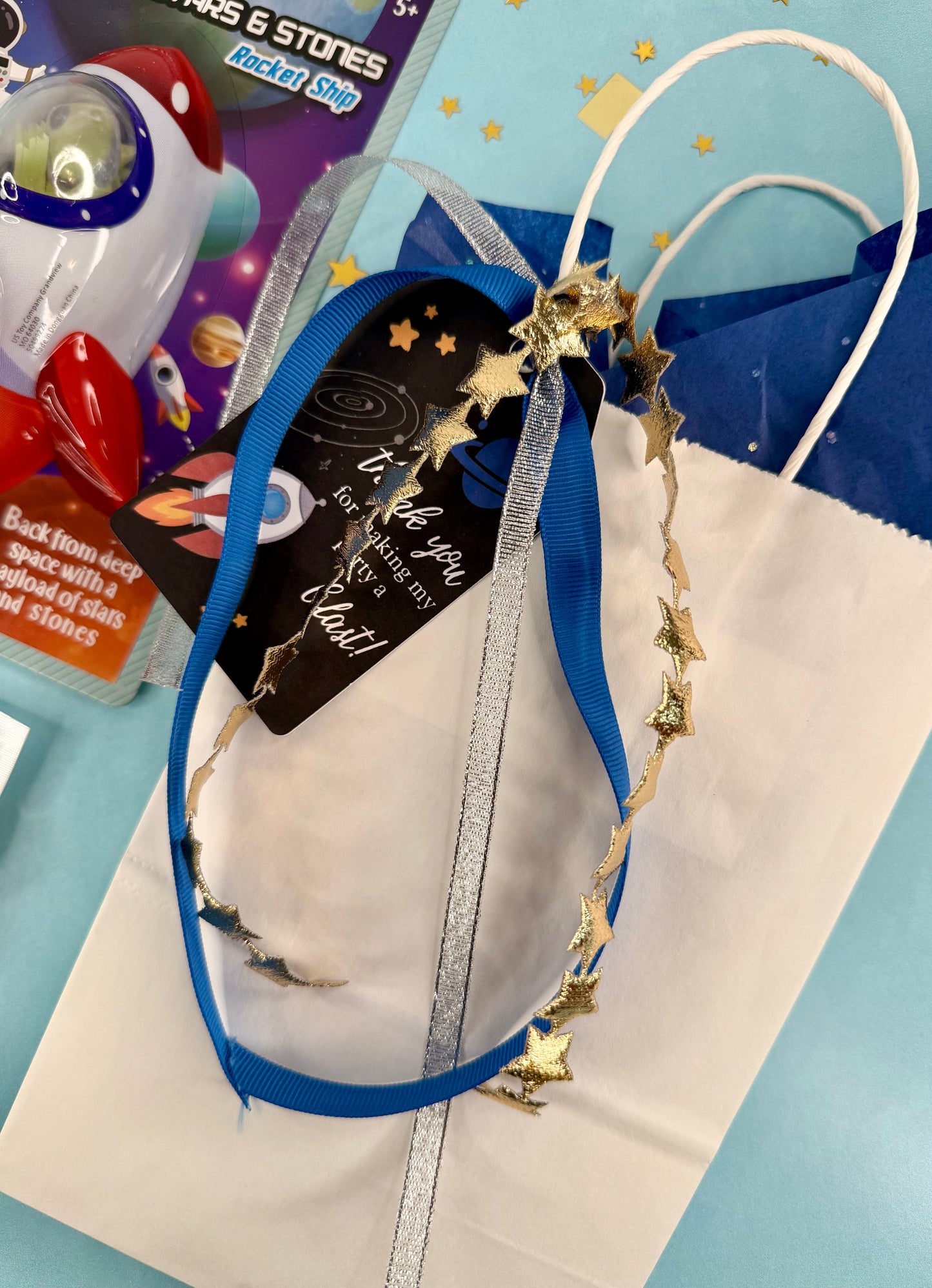 Children's space-themed toy set with a helmet, spaceship, and cards on a blue background.