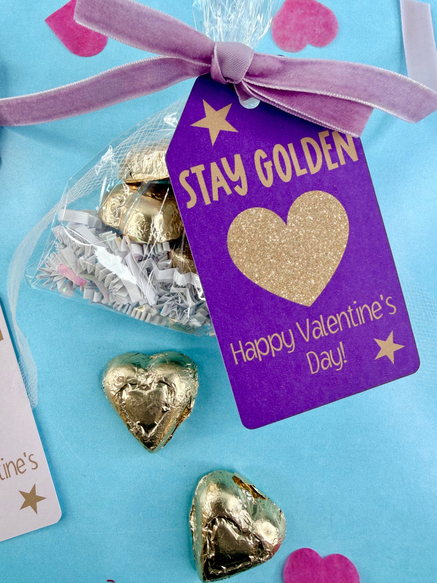 Heart-shaped gold chocolates with a 'Stay Golden Happy Valentine's Day' tag on a blue background.