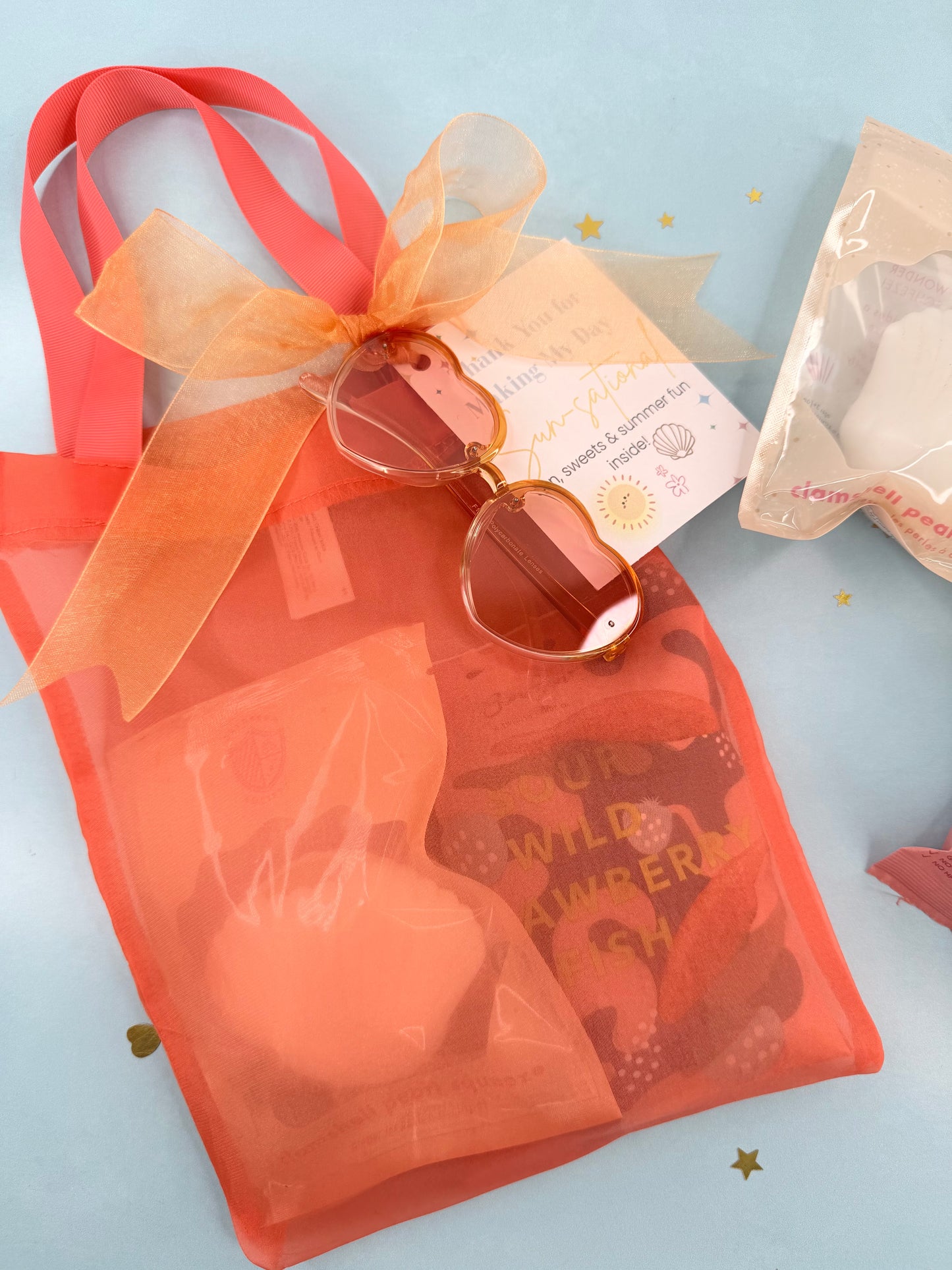 Orange sunglasses with a bow on an orange tote bag against a light blue background