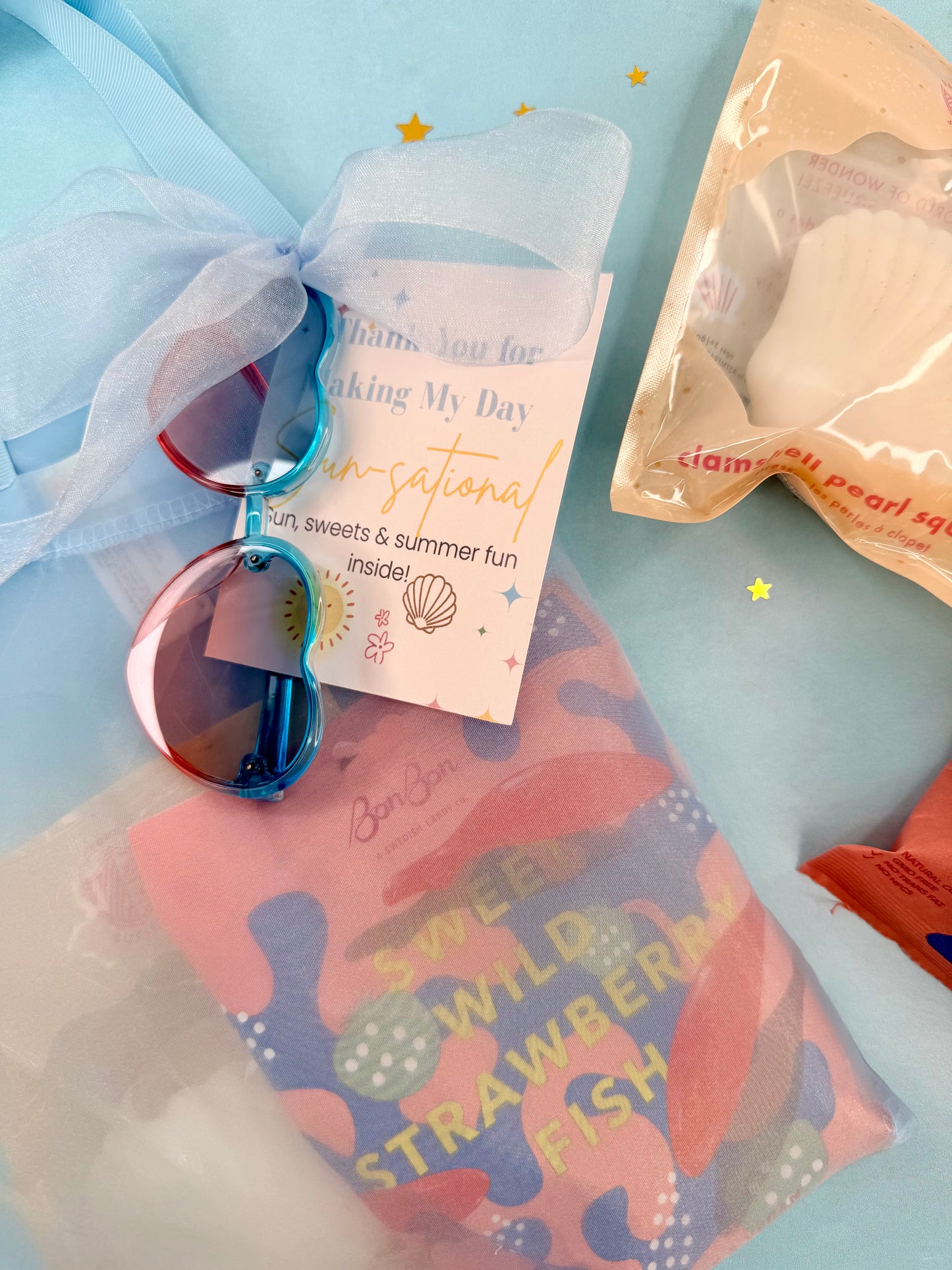 Sunglasses with a card and a bag of candy on a light blue background