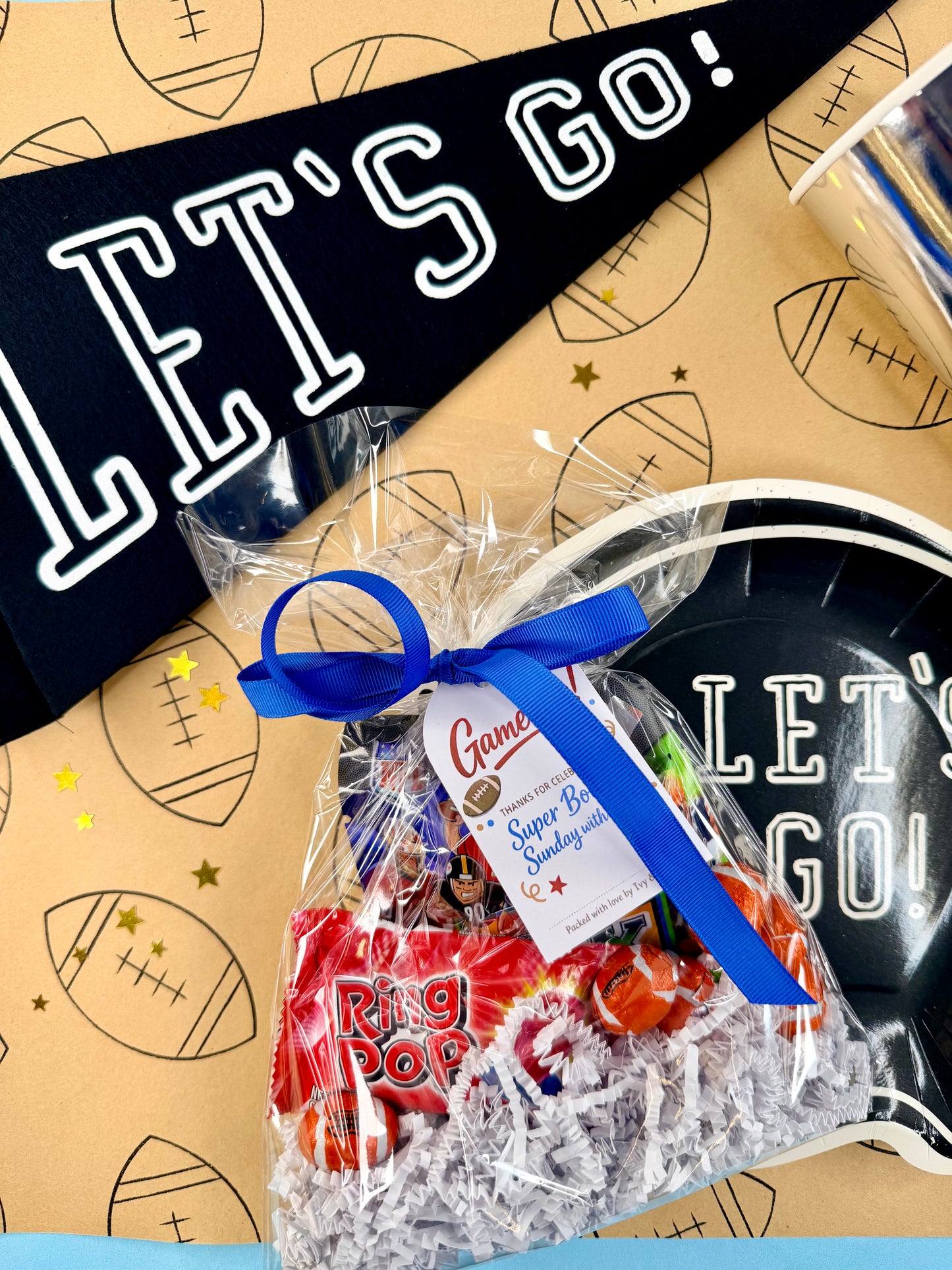 Gift bag with candy and a blue bow on a sports-themed background with 'Let's Go!' text.