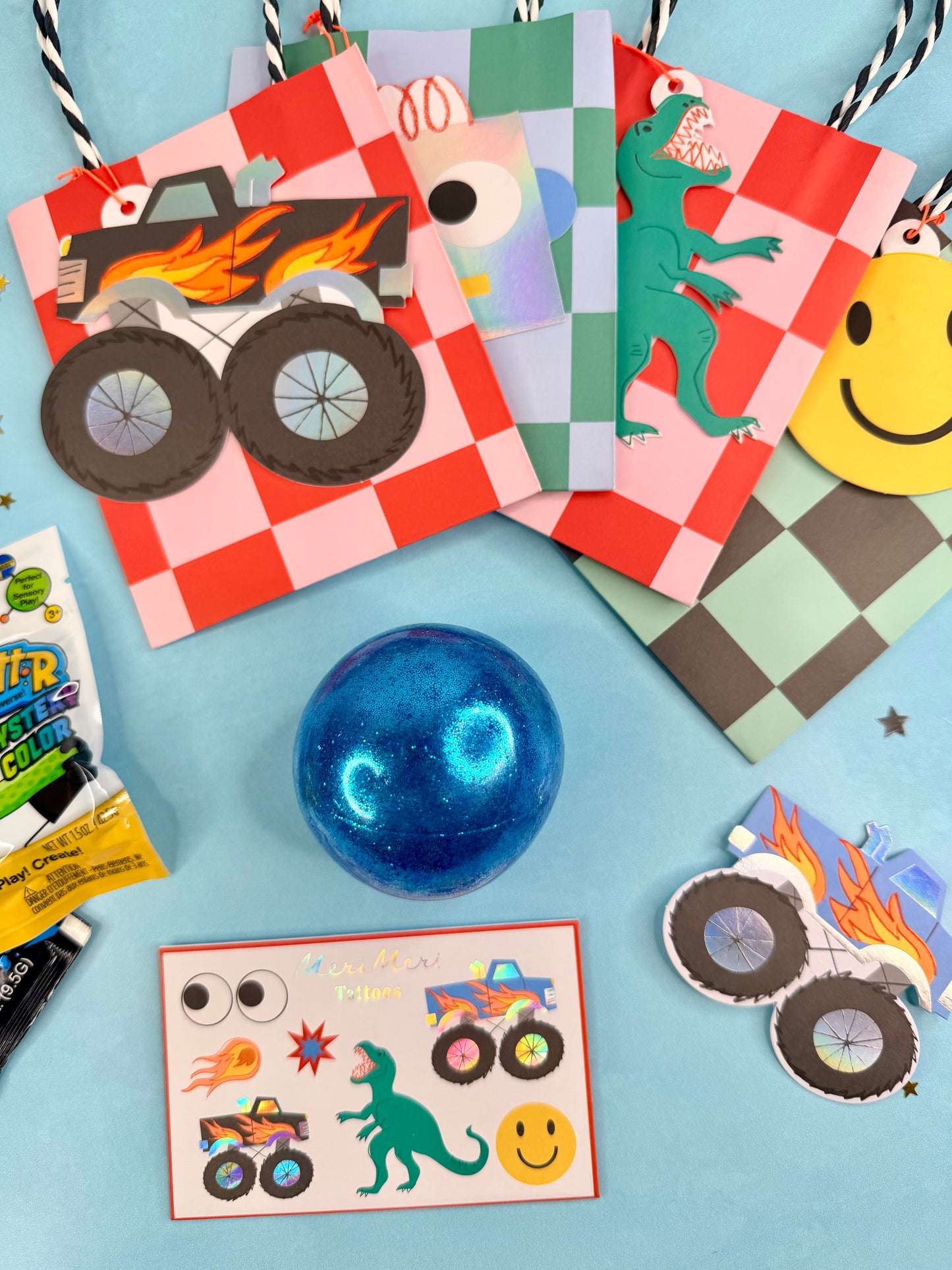 Colorful children's party favors including cards, stickers, and a blue ball on a blue background.