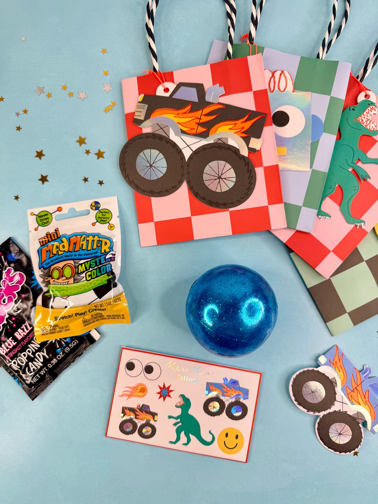 Assorted children's party favors including a bag, candy, and stickers on a blue background.
