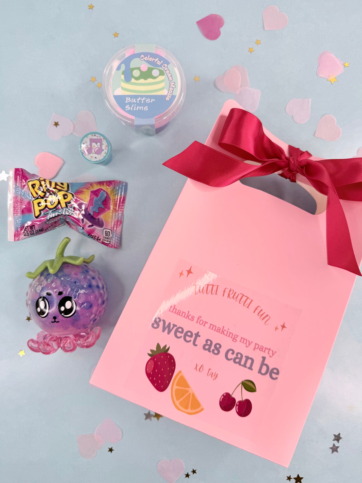 Pink party favor bag with treats on a light blue background