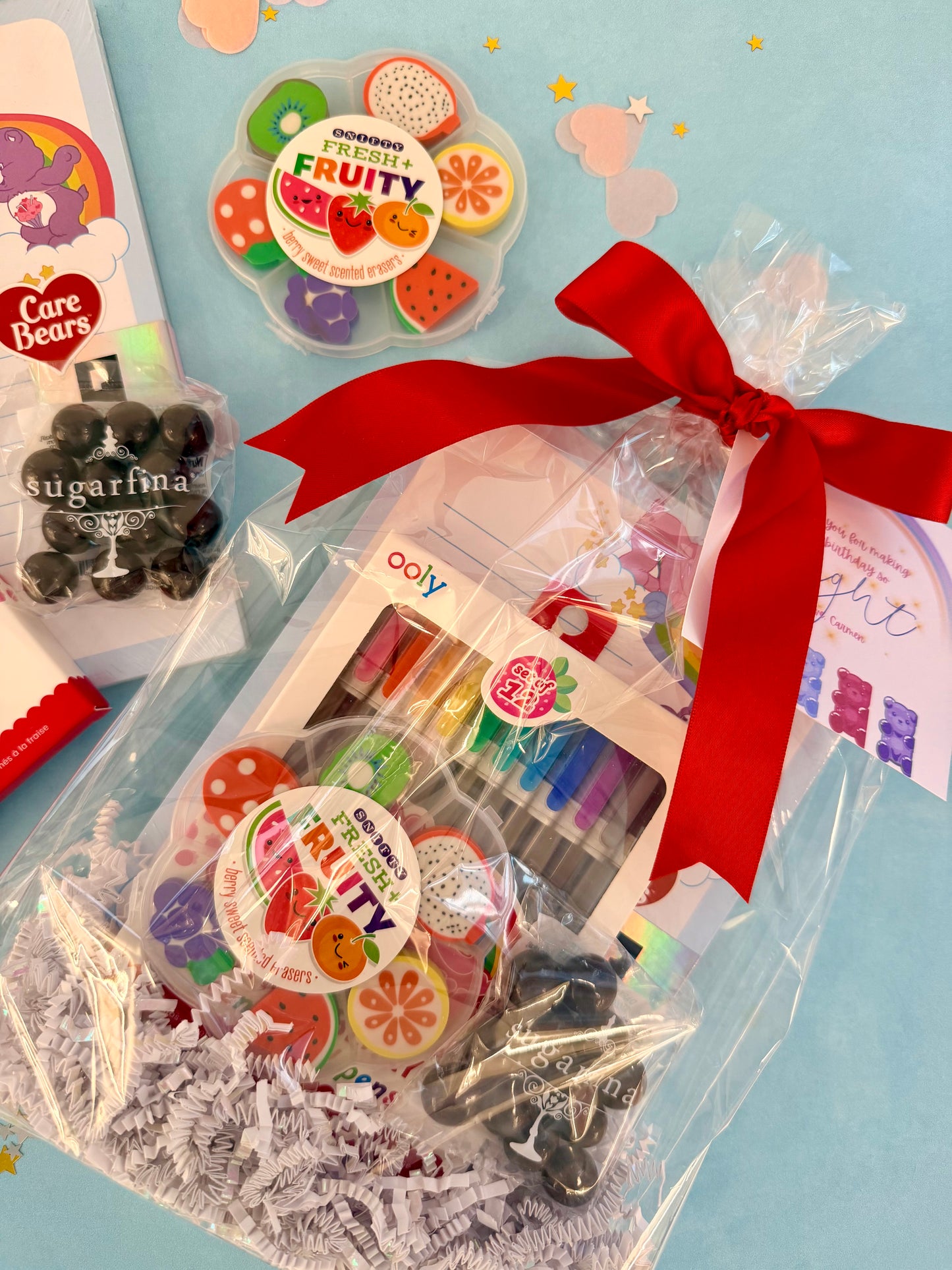 Gift set with colorful candy, a red ribbon, and a card on a light blue background