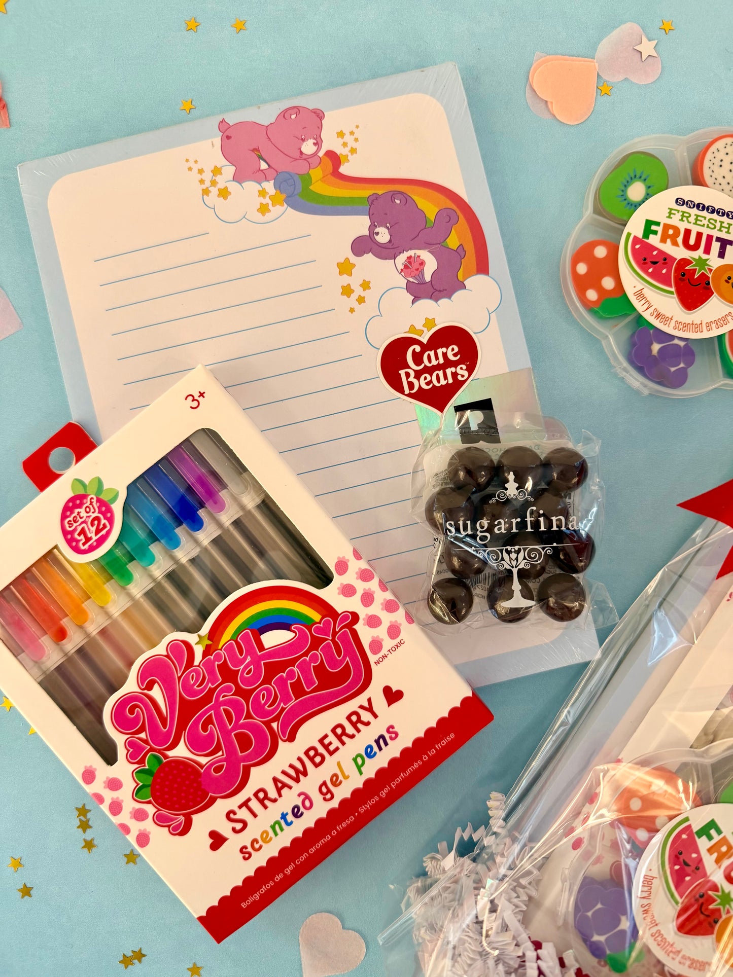 Assorted stationery items including gel pens, stickers, and a notepad on a light blue background.