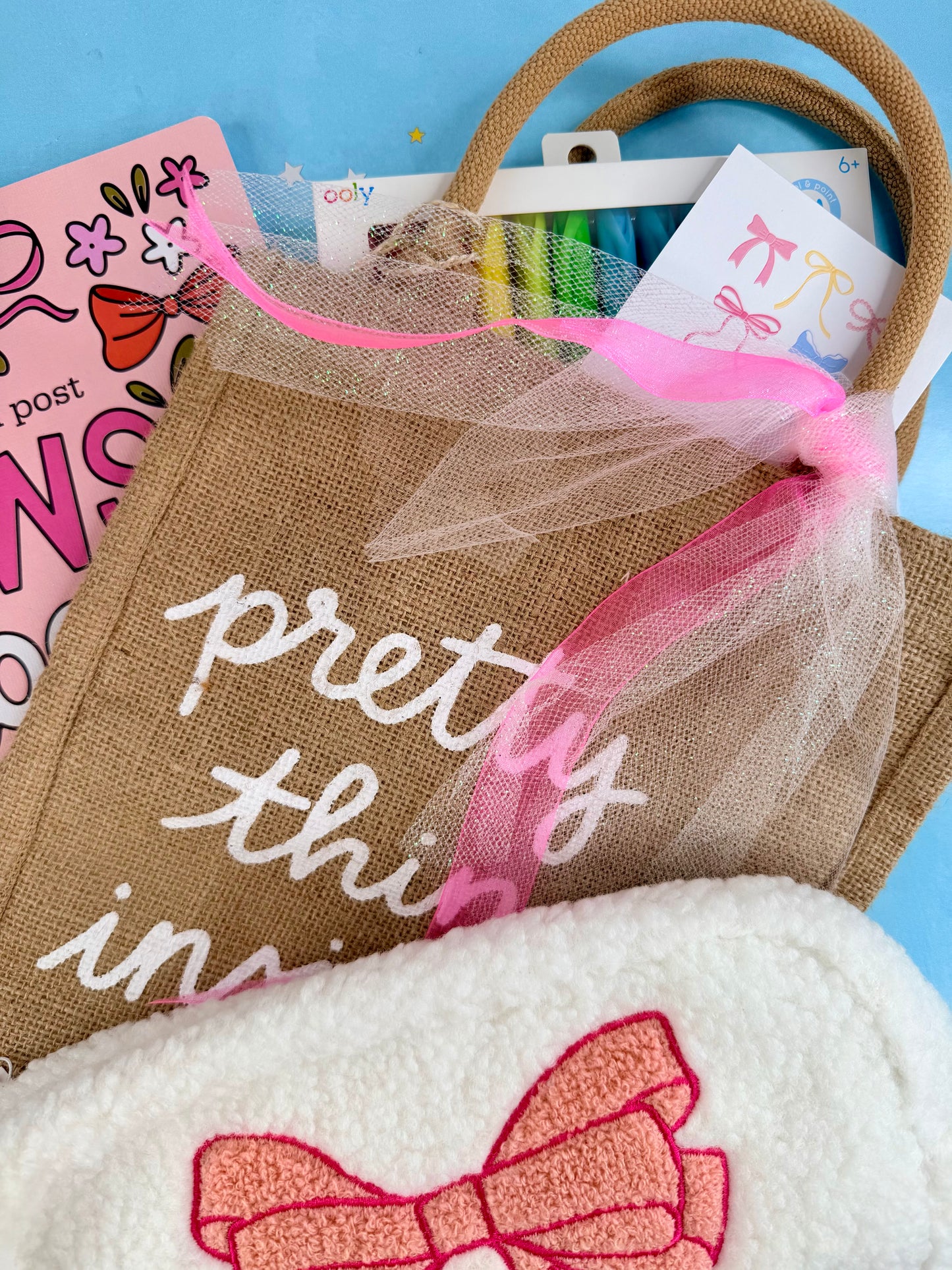Burlap bag with 'pretty thing inside' text, pink tulle, and a close-up of a white item with a red bow on a blue background.