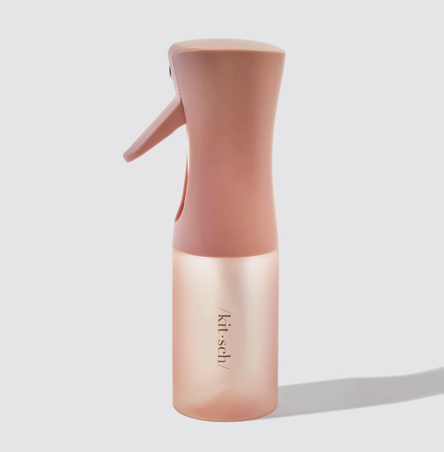 Pink spray bottle with 'kit-sch' branding on a light gray background