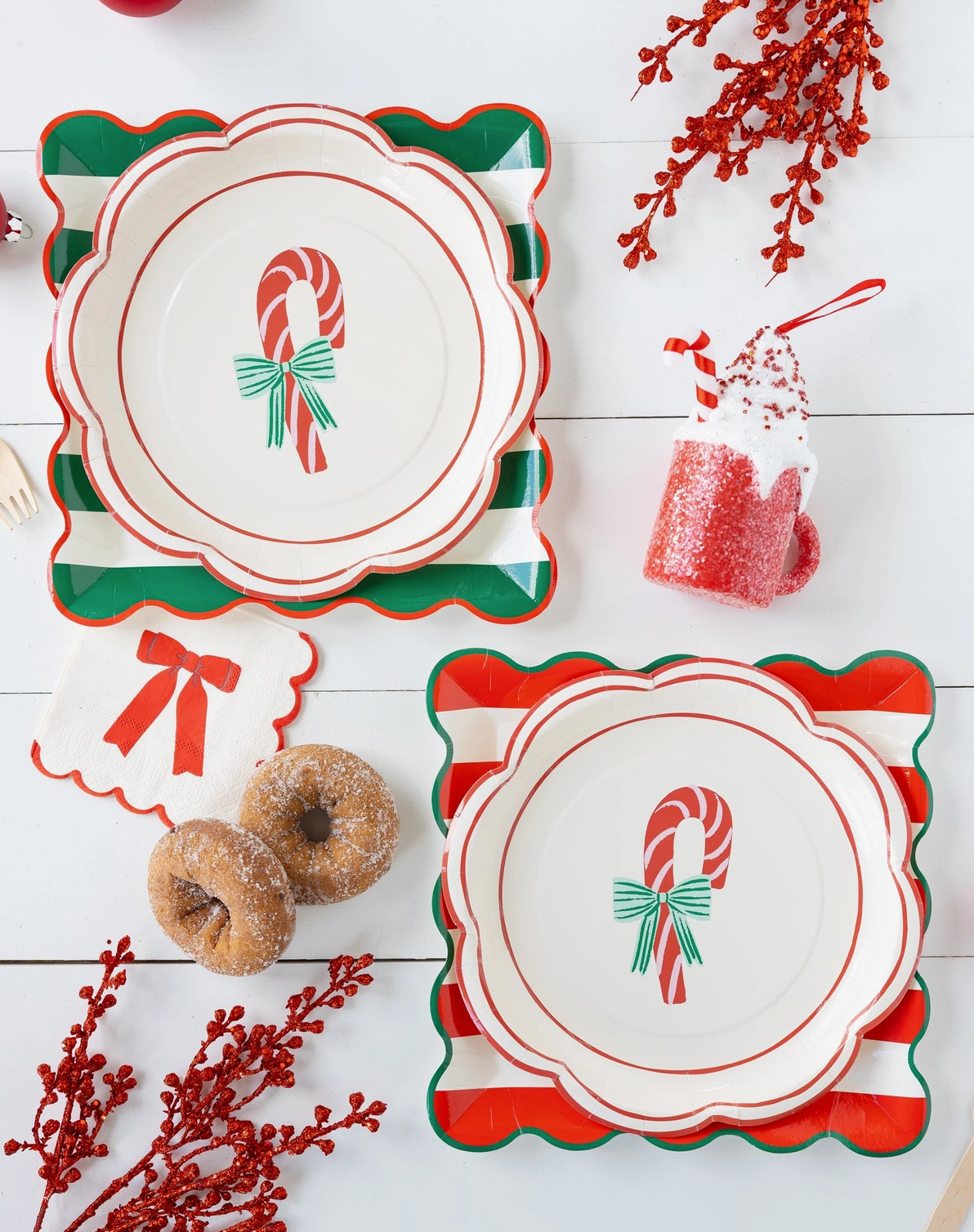 Set of Christmas-themed plates with candy cane and bow designs on a white wooden surface.
