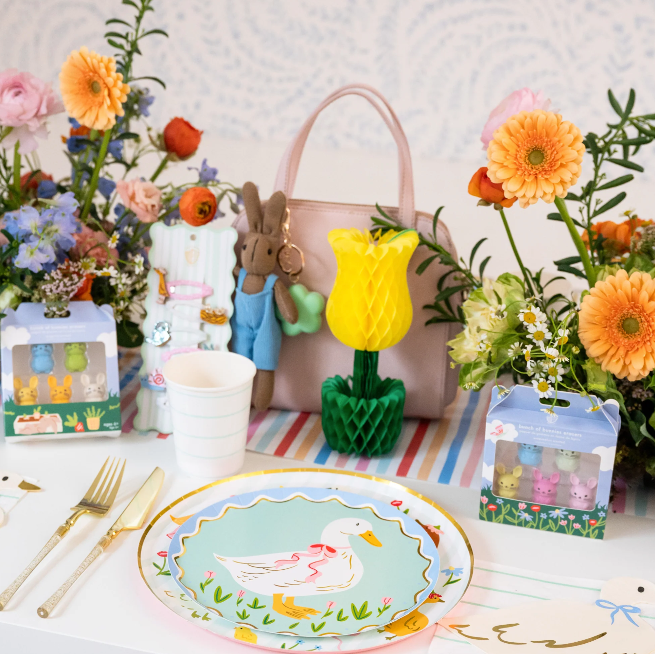 Easter-themed table setting with decorative items, flowers, and a plate featuring a duck design.