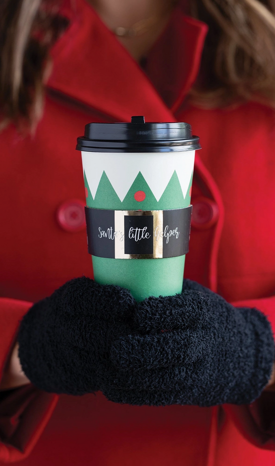 Person wearing black gloves holding a green coffee cup with a festive design.