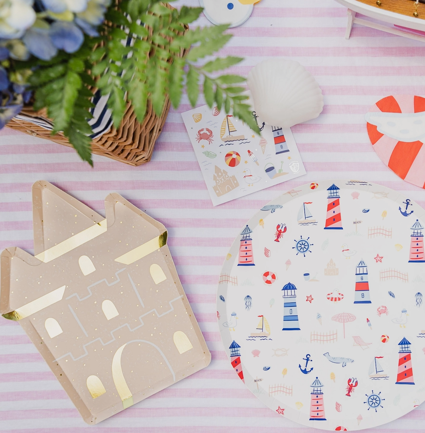 Decorative items including a castle-shaped card and a plate with lighthouse pattern on a pink striped background.