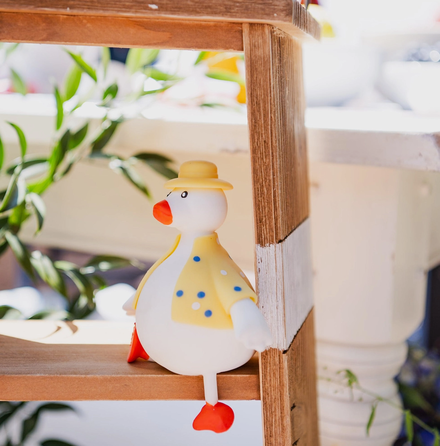 Plush toy duck with a yellow hat on a wooden shelf