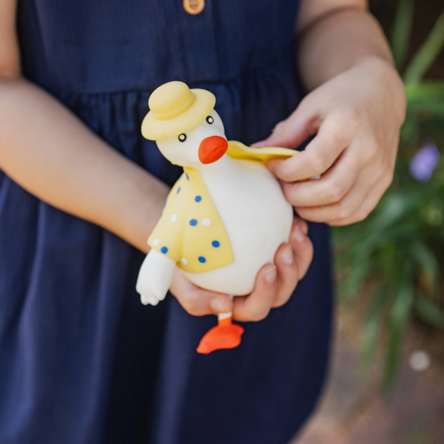 Child holding a toy duck with a yellow hat and outfit