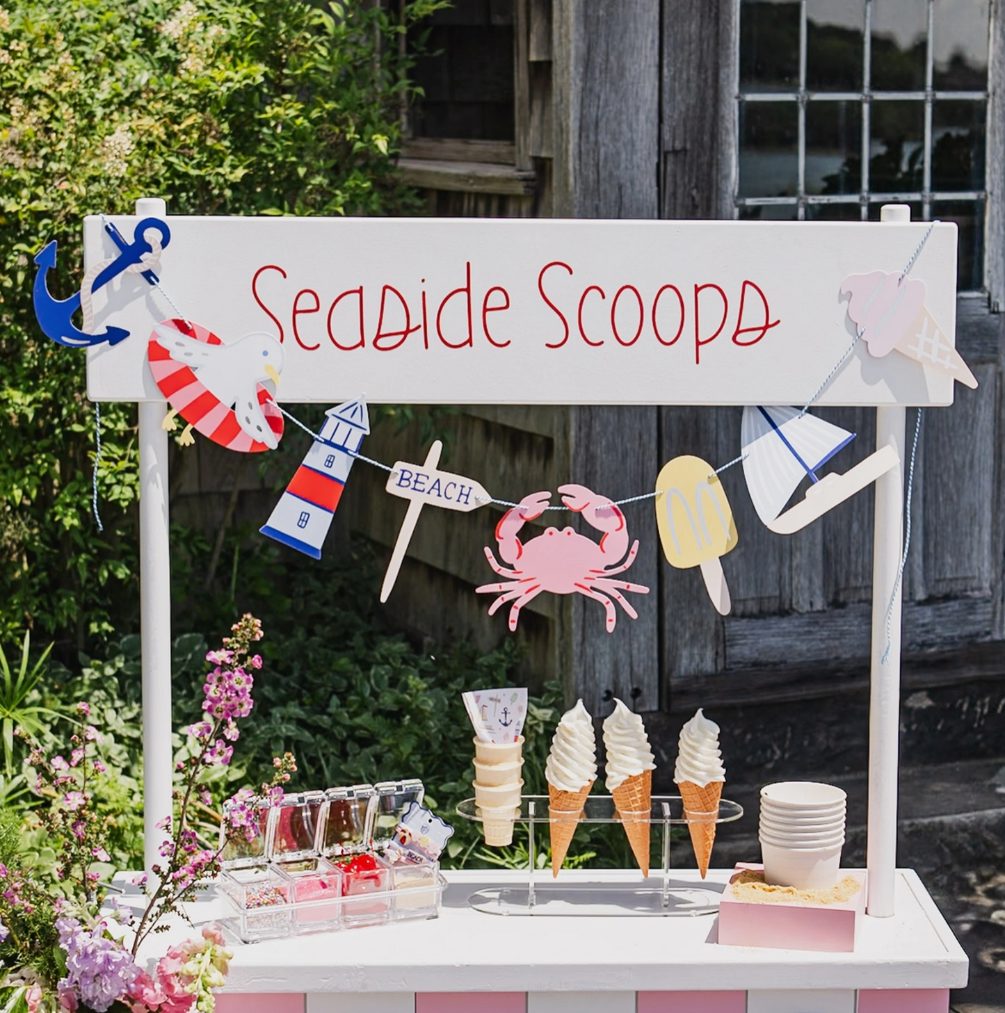 Ice cream stand with 'Seaside Scoops' sign and ice cream cones on a wooden deck.