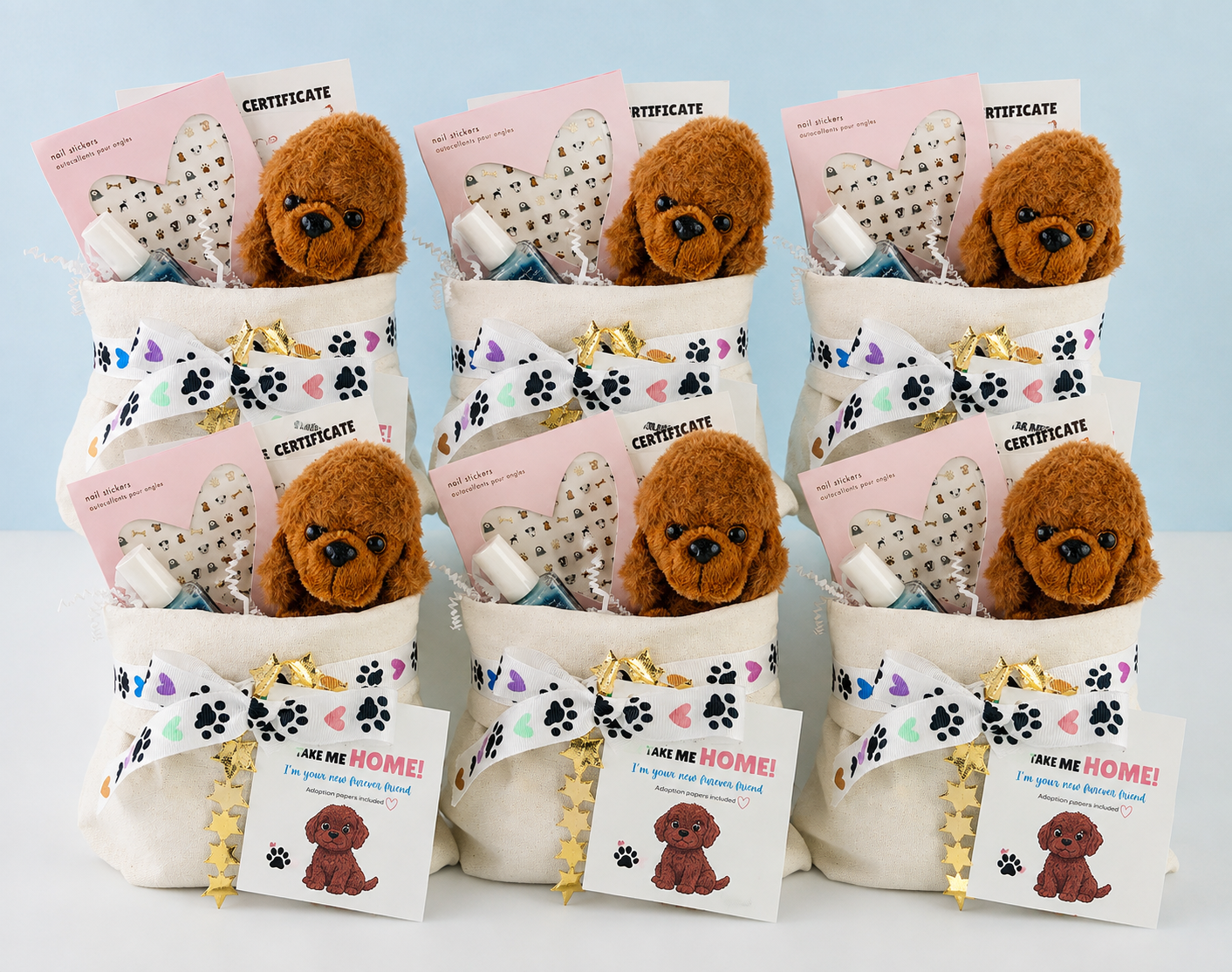 Six small plush dog gift baskets arranged in a grid on a white surface against a pale blue background. Each basket contains a brown stuffed dog face, a cream fabric bag, a white ribbon printed with black paw prints, gold foil stars, a pink certificate card, and a small 'Get Him Home!' gift tag.