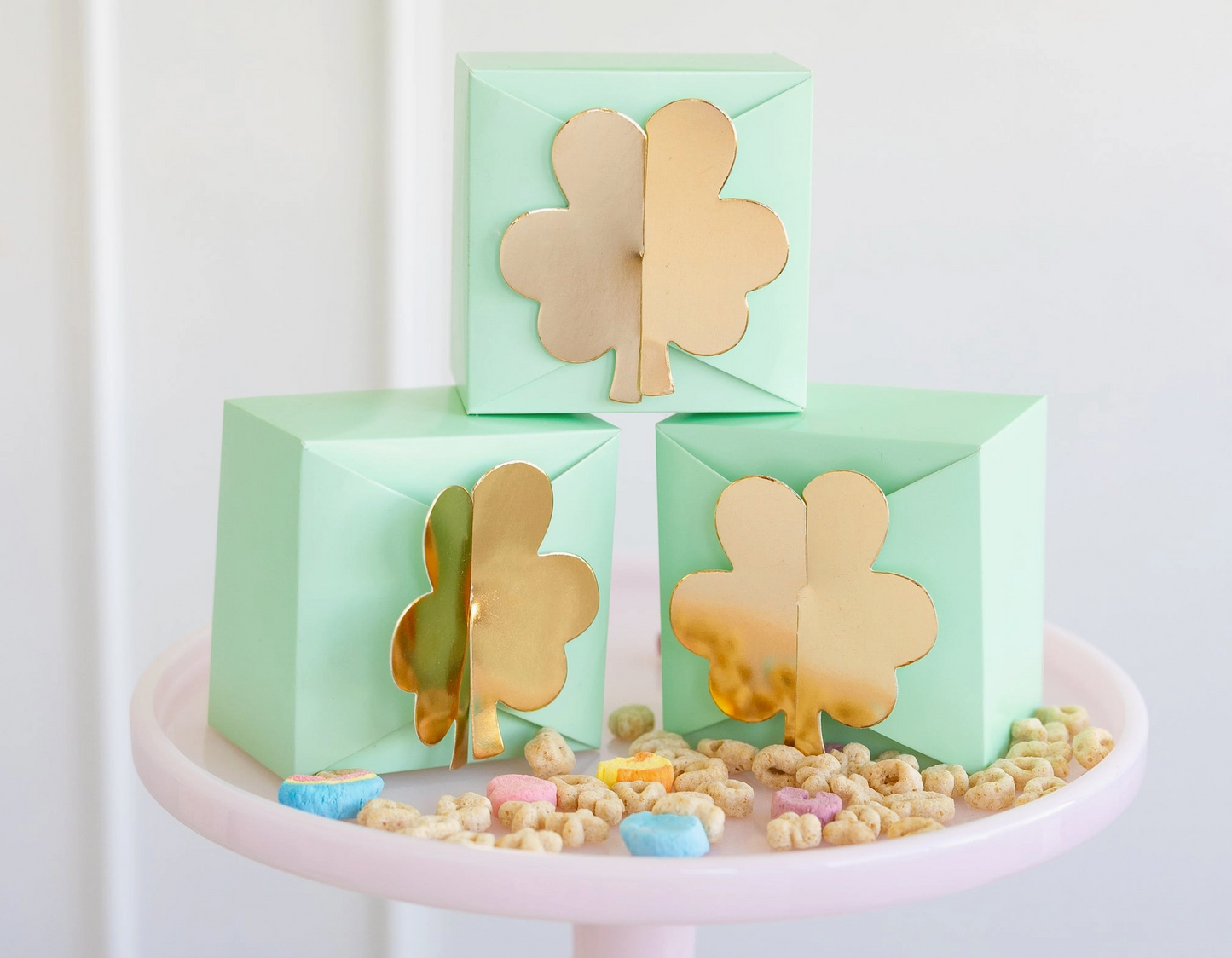 Three green boxes with gold four-leaf clover designs on a white background
