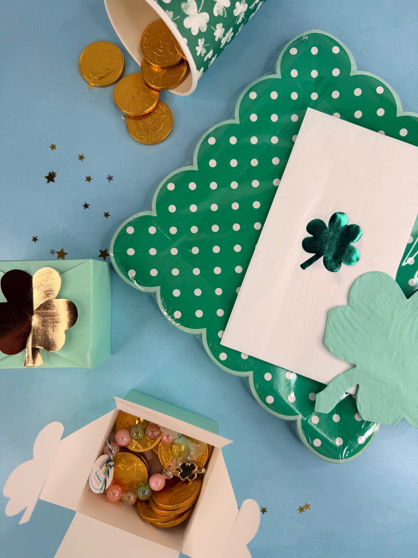 Decorative table setting with shamrock decorations, gold coins, and a polka dot plate on a blue background.