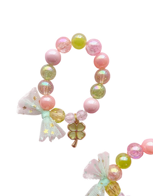 A custom beaded charm bracelet with a gold-colored shamrock charm, predominantly in pastel colors with both glossy and matte finish beads, displayed on a pink background.