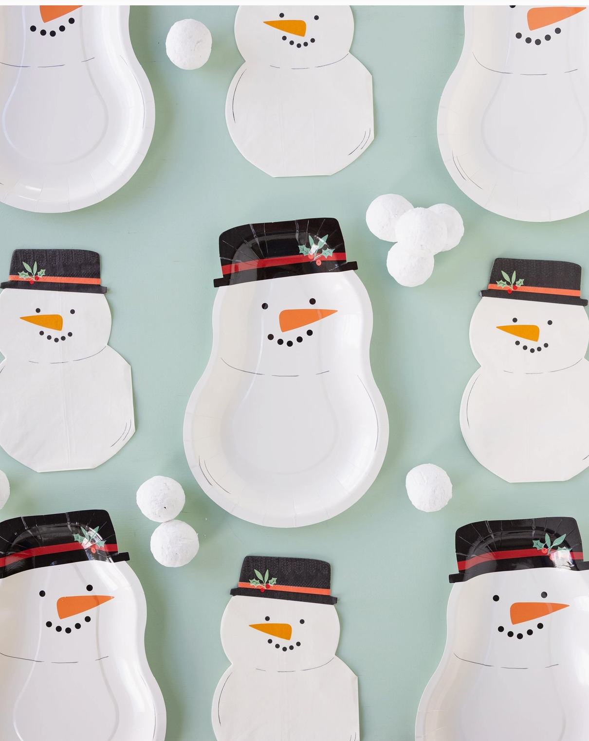Pattern of snowman-shaped paper plates with hats on a light blue background