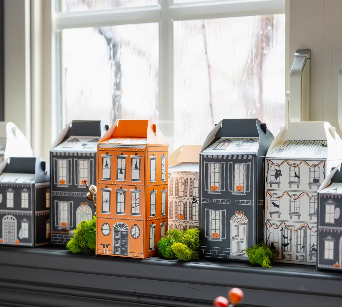 Model houses on a windowsill with a snowy landscape outside