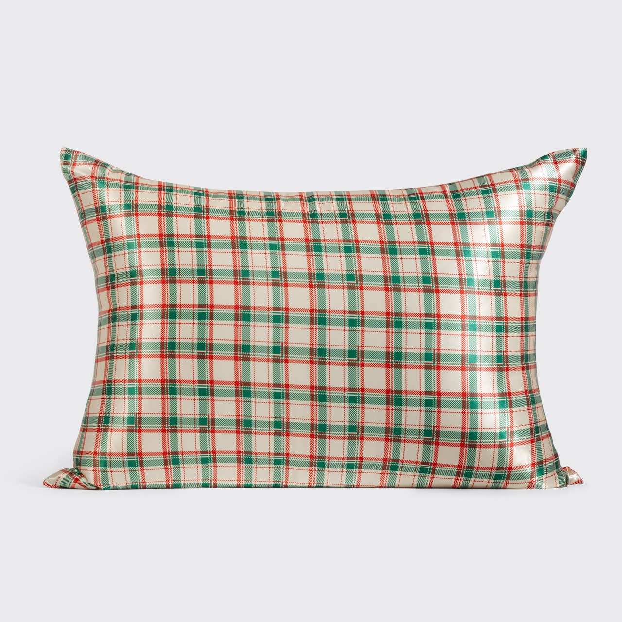A rectangular decorative pillow featuring a classic Christmas-themed plaid pattern in green, red, and cream, set against a solid light gray background.