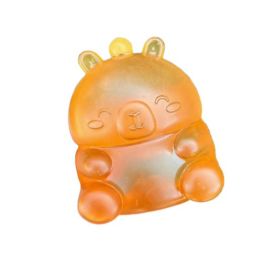 Orange animal-shaped toy held in a hand with grass background
