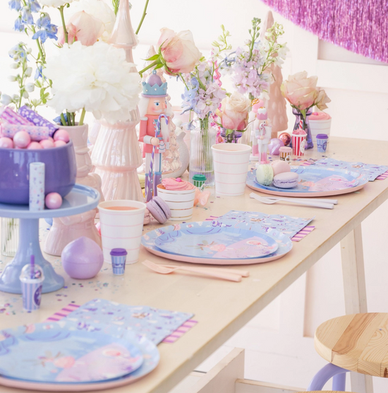 Children's birthday party table setting with pastel colors, plates, and decorations.