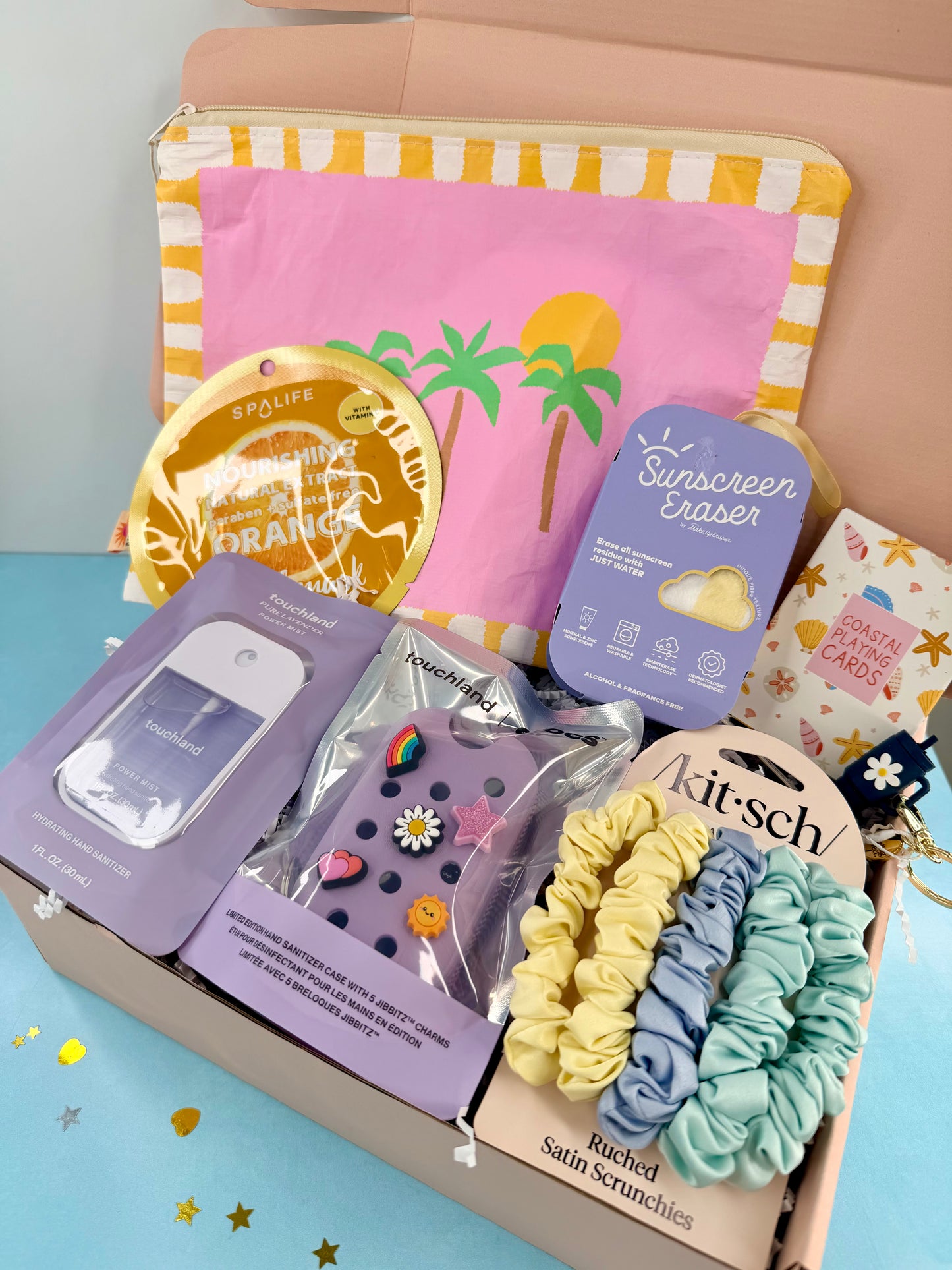 Assorted beauty and lifestyle products including scrunchies, sunscreen eraser, and lip balm in a box.
