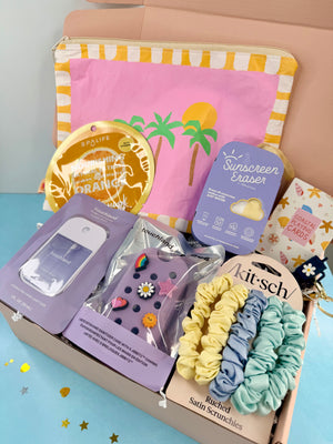 Assorted beauty and lifestyle products including scrunchies, sunscreen eraser, and lip balm in a box.