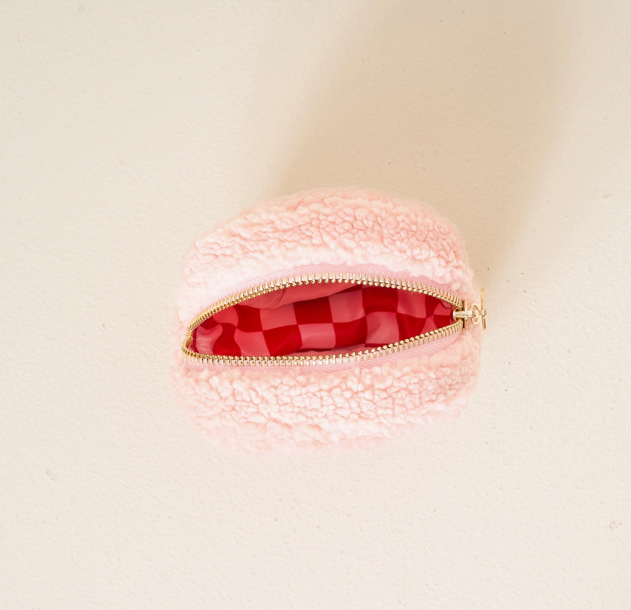 Pink textured pouch with a red interior on a beige background