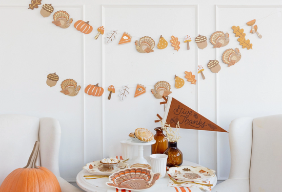 Thanksgiving-themed table setting with decorative elements on a white wall.