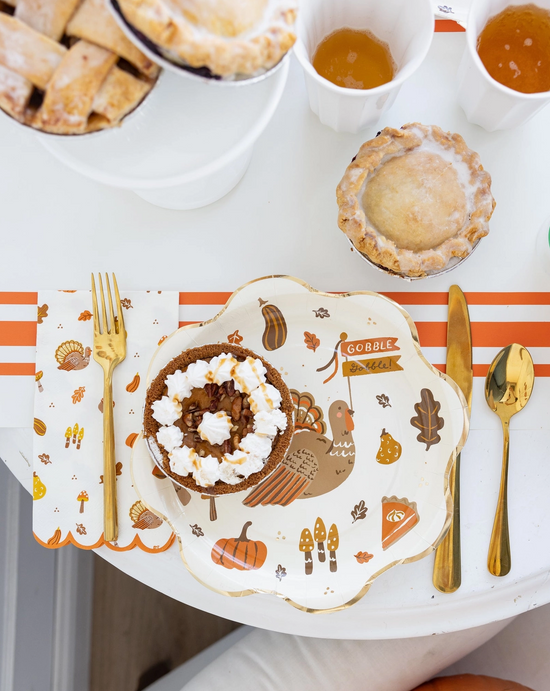 Thanksgiving-themed plate with a dessert, cutlery, and a decorative placemat on a table.