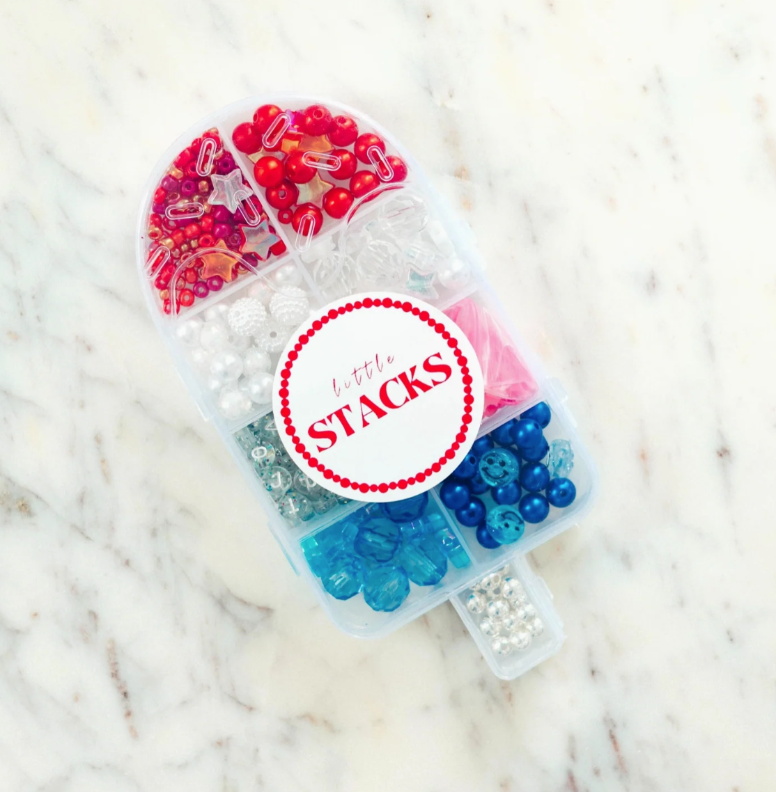 Colorful beaded containers with 'Little Stacks' branding on a marble surface