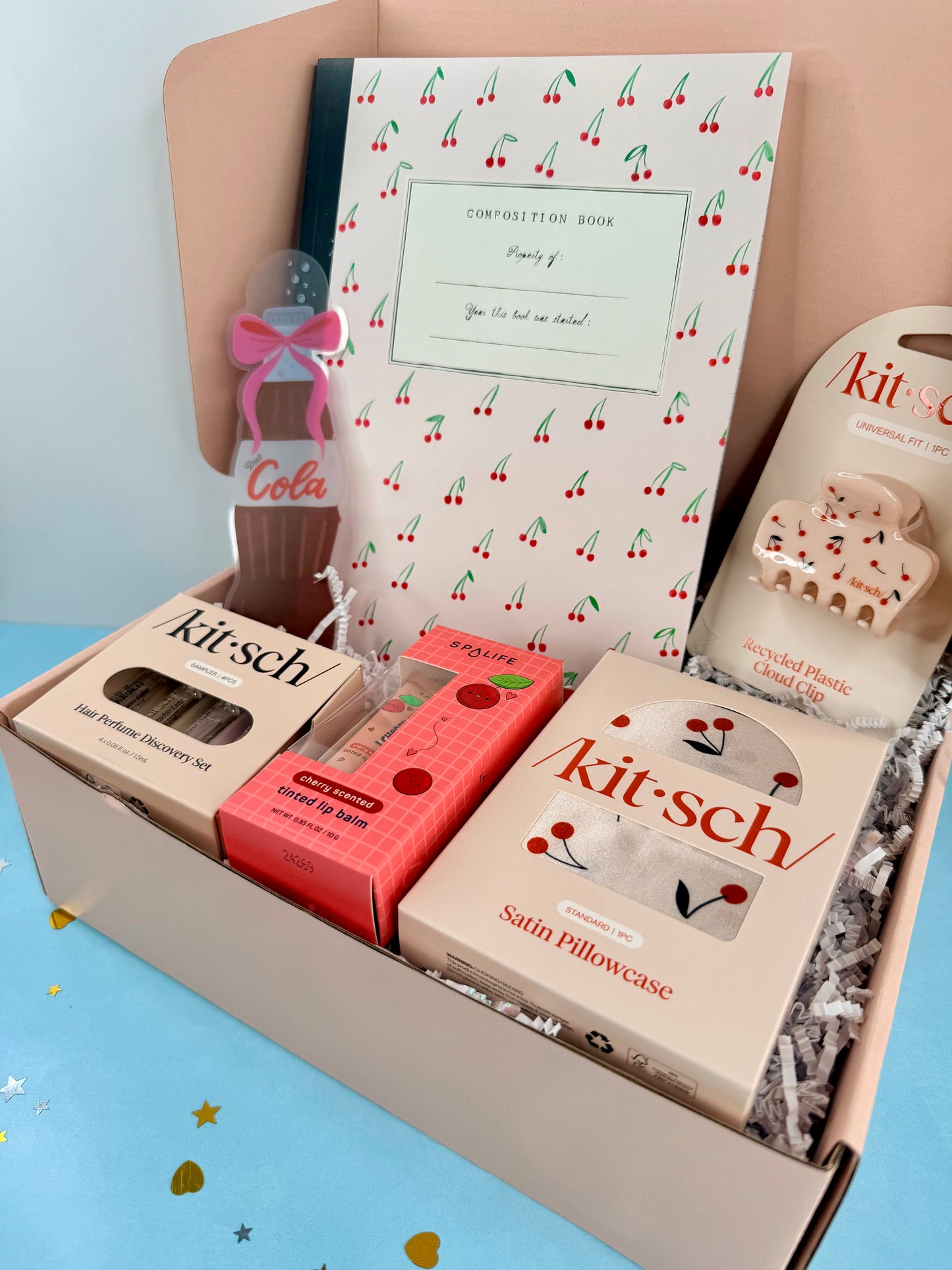 Gift box with various items including a pillowcase, soap, and a small bottle labeled 'Cola'.
