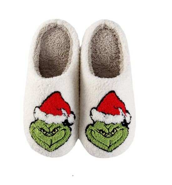 Pair of white slippers with Grinch face design on a white background