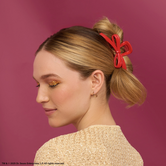 Woman with a red hair bow against a pink background