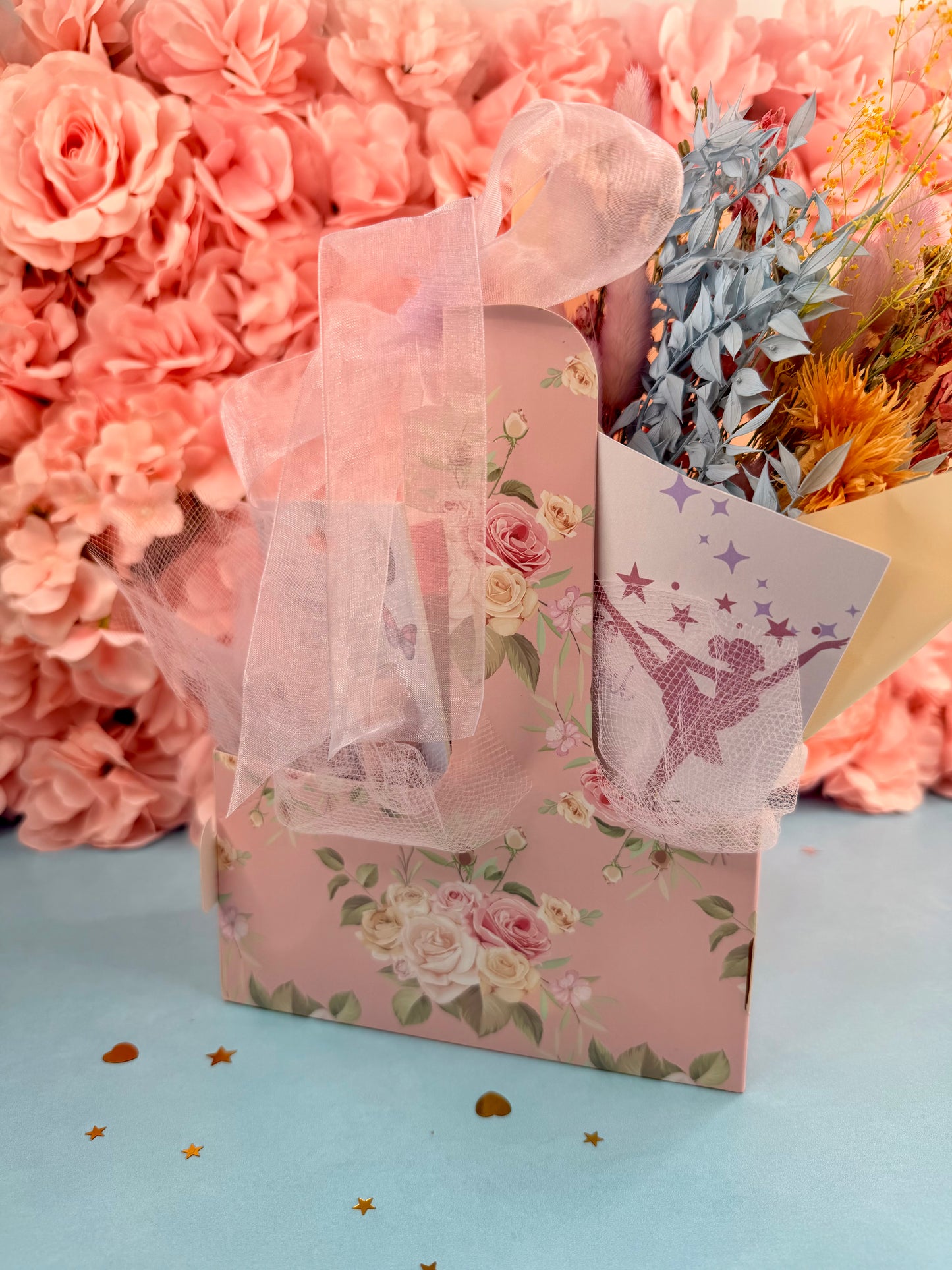 Decorative gift bag with floral design and ballet dancer illustration against a pink floral background.