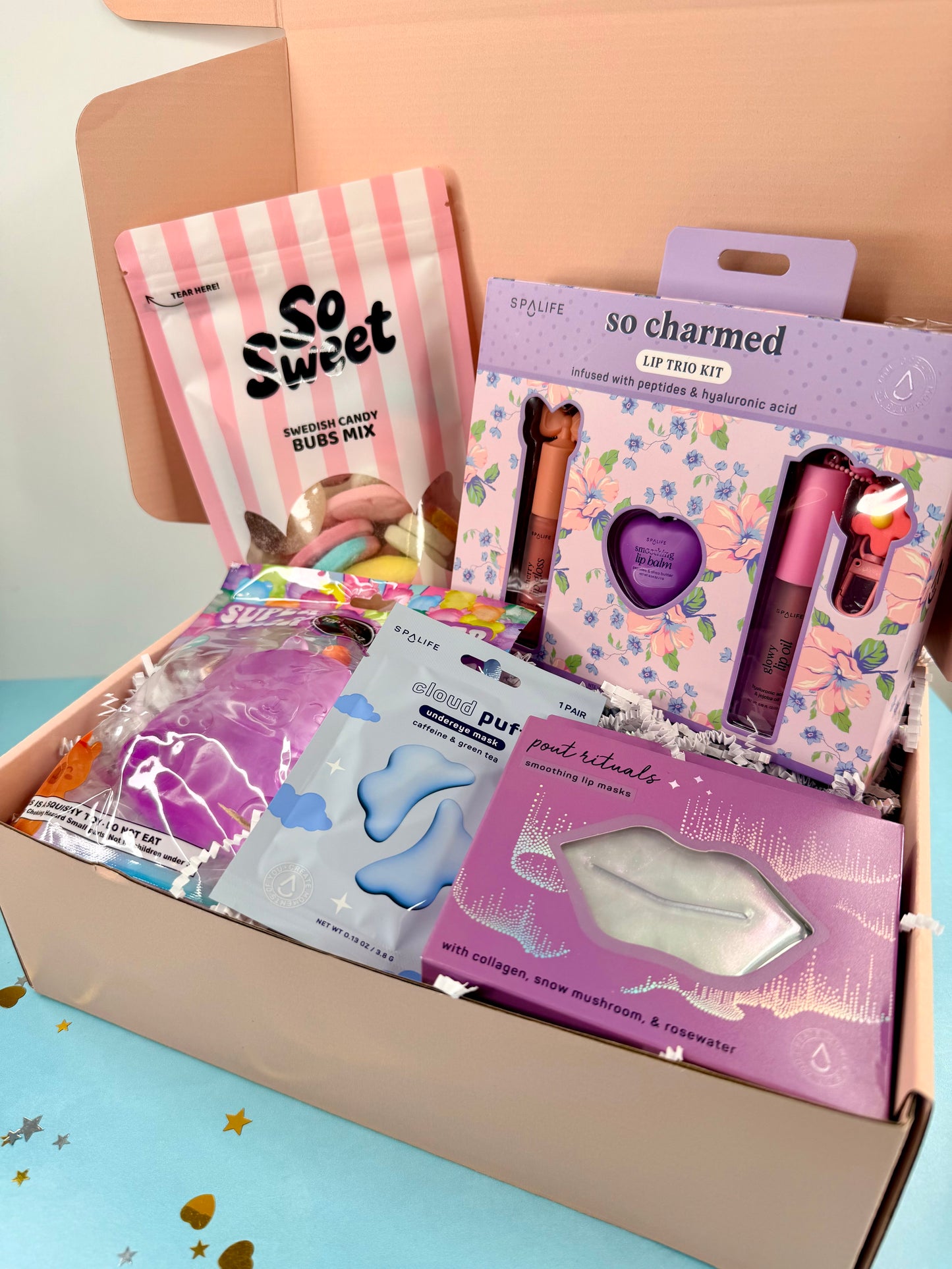 Open box containing various beauty products with visible branding on a light blue surface.