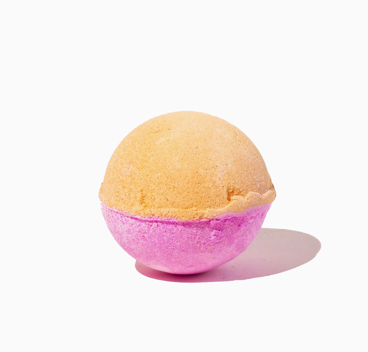 Bath bomb with peach and pink gradient on a white background