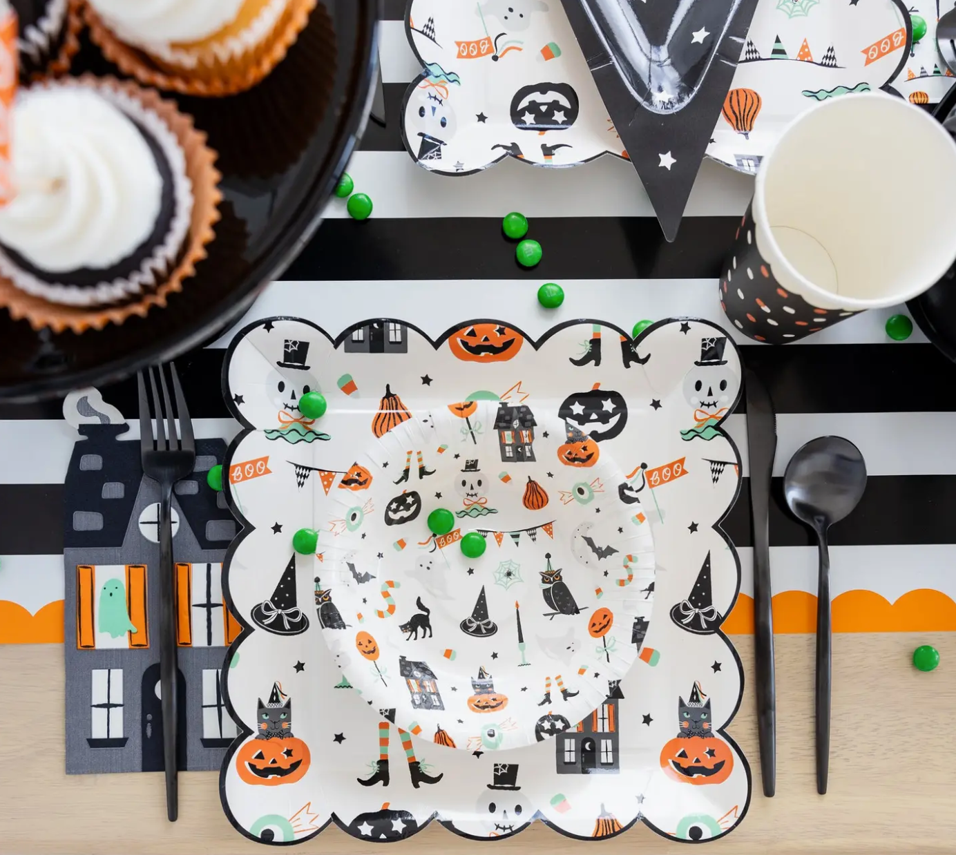 Halloween-themed table setting with decorative plates, cups, and utensils.
