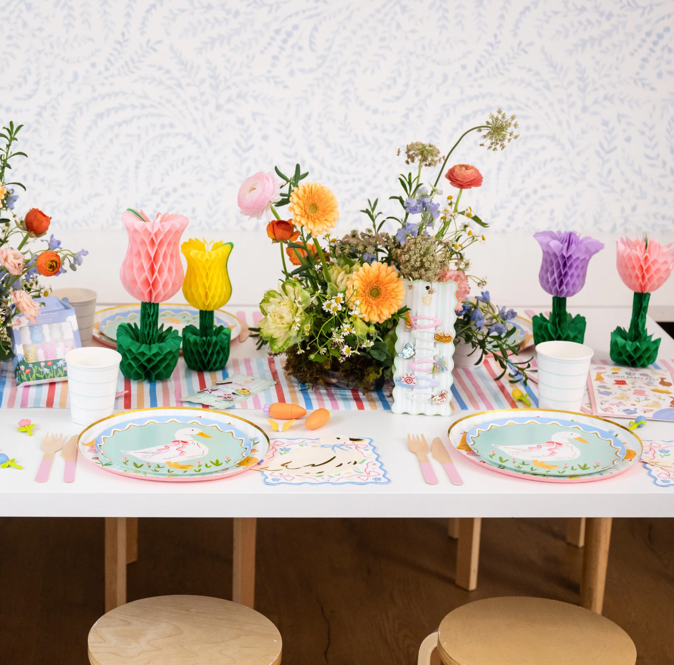 Children's table setting with floral decorations and colorful plates.